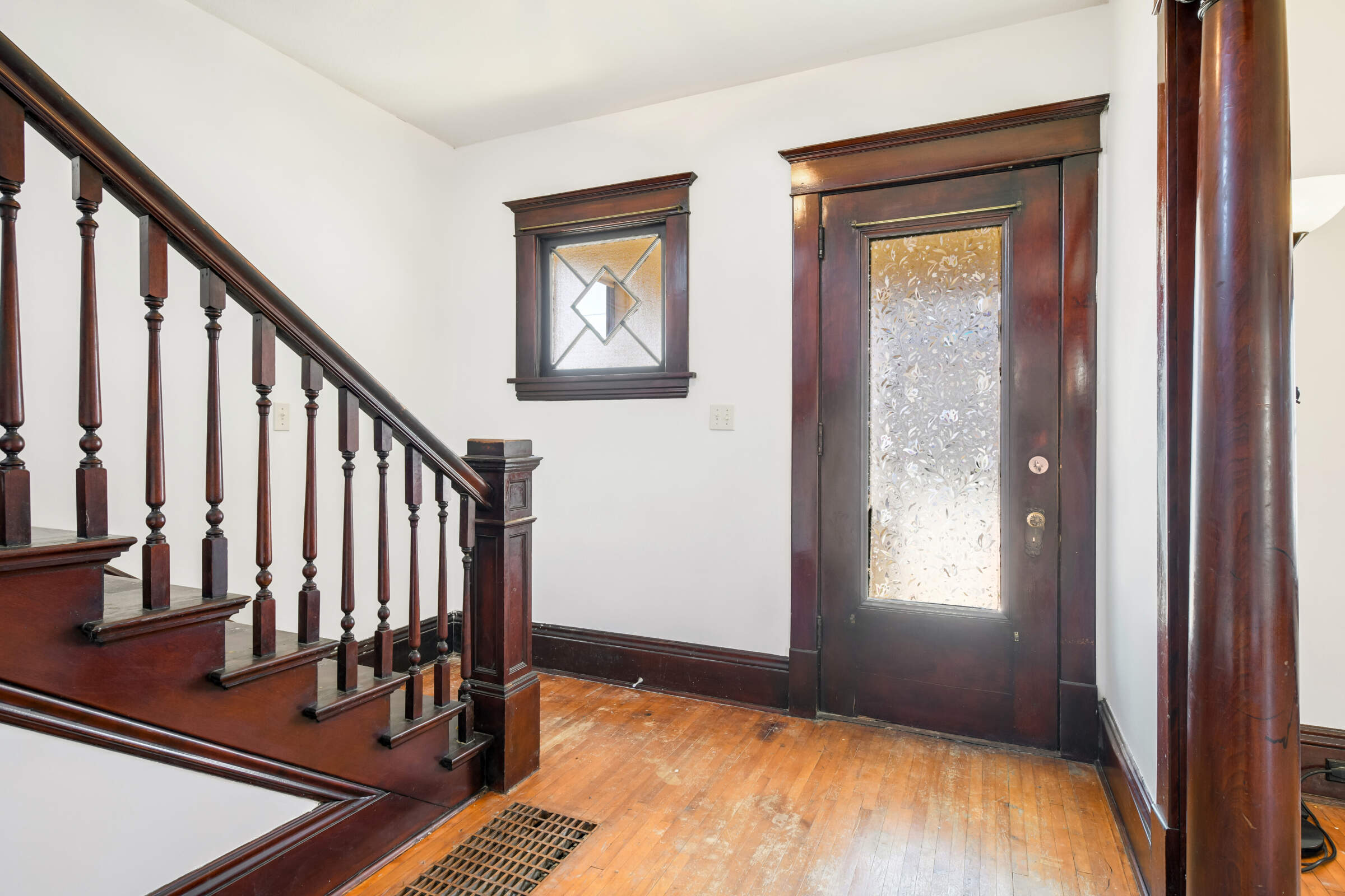 Gorgeous glasswork and spindle staircase to the upper level adds style and drama to the front entry